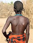 Une coiffure finement tressée d'un jeune homme Dassanetchs.La scarification du bas du dos est un signe de beauté. Il porte un tabouret en bois dans sa main gauche, qui se double d'un oreiller pendant la nuit.Le Delta de l'Omo du sud-ouest de l'Éthiopie est une des parties moins accessibles et les moins avancés d'Afrique de l'est.