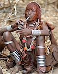 A Hamar woman blows a tin trumpet at a Jumping of the Bull ceremony.The Hamar are semi nomadic pastoralists of Southwest Ethiopia whose women wear striking traditional dress and style their red ochred hair mop fashion.The Jumping of the Bull ceremony is a rite of passage for young men.
