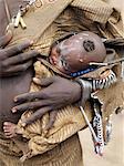 A Mursi child is carried safely in her mothers decorated leather garments.The Mursi speak a Nilotic language and have affinities with the Shilluk and Anuak of eastern Sudan.They live in a remote area of southwest Ethiopia along the Omo River.