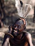 Un homme de Turkana arbore un beau tableau de plumes d'autruche de sa coiffure d'argile.Ayant écarté l'inconfort de l'ornement de l'ivoire pour les lèvres, il doit introduire un petit tampon en bois dans le trou sous sa lèvre inférieure pour éviter les dribbles. Le couteau traditionnel de poignet Turkana, il porte sur son poignet droit.