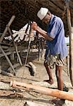 Ein Schiffsbauer bohrt ein Loch um Holz Segelboot bei Faza Pate Insel zu reparieren. Die Jahrhunderte alte Technik des Bohrers Bogen er verwendet ist ideal für Orte, wo es keinen Strom gibt. Die wechselvolle Geschichte der Faza stammt aus mehreren hundert Jahren.