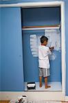 boy painting wall in closet