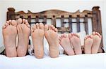 famille couché sur le lit, les pieds alignés