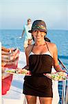 femme sur yacht tenant des assiettes de nourriture