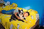 boy napping with dog on bed