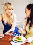 Zwei junge Frauen bei einem Abendessen, Schweden lächelnd.