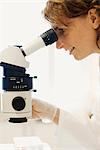 Weibliche Forscher mit einem Mikroskop im Labor.