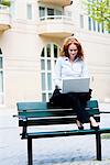 Woman sitting on a bench using her laptop, Stockholm, Sweden.