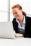 Smiling woman sitting in front of a laptop, Sweden.