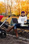 A mother with a perambulator using a laptop, Sweden.