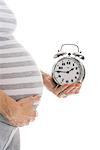 A pregnant woman holding a clock.