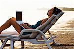 A Scandinavian teenage girl with a laptop by the sea, Thailand.