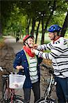 A couple helping each other fastening a cycle helmet, Sweden.