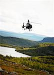 Helicopter flying above a mountain scenery, Sweden.