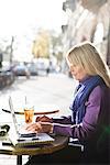 Jeune femme assise dans un café à l'aide d'un ordinateur portable, Suède.