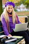 Une femme, assis sur un banc dans un parc à l'aide d'un ordinateur portable, Stockholm, Suède.