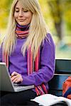 Eine Frau sitzend auf Bank in einem Park mit einem Laptop, Stockholm, Schweden.