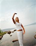 Jeune femme pratiquant l'yoga par un lac, Suède.