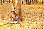 Jeune fille tenant un chien caniche de feuilles