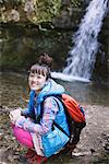 Amused Young Woman Hiker Near Waterfall