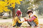 Boy And Girl Sitting In Autumn Leaves