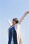 Japanese Teenage Girl Against Blue Sky Arms Outstretched