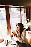 Fille japonaise assis dans un Restaurant tenue livre