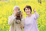 Middle-Aged Japanese Couple Snapping In Meadow