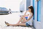 Young Woman Sitting Against Wall In Street