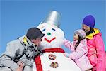 Parents avec leur fille faisant le bonhomme de neige