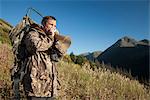 Male moose hunter using a moose call to call in moose, Bird Creek drainage area, Chugach Mountains, Chugach National Forest, Southcentral Alaska, Autumn