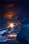 Worker cuts metal fittings off a boat hull using an oxy-acetylene cutting torch, Kodiak Boatyard, Saint Herman Harbor, Kodiak, Near Island, Southwest Alaska, Autumn