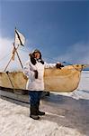 Mâle chasseur Inupiaq Eskimo, debout à côté d'un Inupiaq Umiaq fait de peau de phoque barbu (Ugruk), tout en portant une parka traditionnelle des Esquimaux (Atigi) et le sceau peau hat, mer des Tchouktches près de Barrow, Alaska Arctique, été