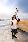 Mâle chasseur Inupiaq Eskimo, debout à côté d'un Inupiaq Umiaq fait de peau de phoque barbu (Ugruk) tout en portant une parka traditionnelle des Esquimaux (Atigi) et seal skin hat, mer des Tchouktches près de Barrow, Alaska arctique, été