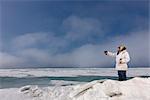Männliche Inupiak Eskimo Jäger stehend auf einem Eis Druck während des Tragens einer traditionellen Eskimo Parka (Atigi) und Siegel Haut Hut, Tschuktschensee in der Nähe von Barrow, Alaska Arktis, Sommer