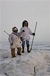 Mâles et femelles Inupiaq Eskimo chasseurs portant leur parka Eskimo (Atigi) portent un fusil et un bâton de marche tout en surplombant la mer des Tchouktches, Barrow, l'Alaska arctique, été