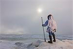 Mâle chasseur Inupiaq Eskimo portant son parka Eskimo (Atigi) et transportant une marche collent tout en surplombant la mer des Tchouktches, Barrow, l'Alaska arctique, été