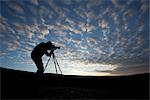 Photographer silhouetted as he photographs on top of Blueberry Hill near Wonder Lake, Denali National Park and Preserve, Interior Alaska, Autumn