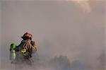 An Anchorage Fire Department firefighter stands atop the roof of a downtown motel while working to extinguish the blaze, Southcentral Alaska, Winter