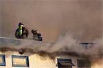 Zwei Feuerwehrmänner in Anchorage Feuerwehr stand auf dem Dach ein Innenstadt Motel während der Arbeit zu löschen die Blaze, South Central Alaska, Winter