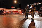 Two Anchorage Fire Department firefighters discuss options on a cold winter night while fighting a fire at the King's Court apartment buildings near downtown, Southcentral Alaska, Winter