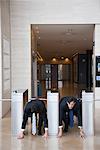 Businessmen crouching in starting position in lobby turnstiles