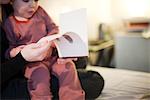 Garçon petit enfant assis sur les genoux du parent, livre, recadrée en regardant