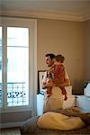 Father holding toddler son, looking out window