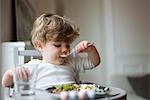 Toddler boy feeding himself with spoon