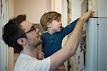 Toddler boy helping father using microwave