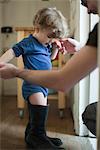 Toddler boy learning to walk in father's boots