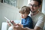 Père regarder bambin garçon, à l'aide de la tablette numérique avec une expression de surprise
