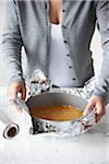 Woman Wrapping Aluminum Foil Around Crust Lined Springform Pan