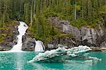 An iceberg from South Sawyer Glacier floats near a waterfall in Tracy Arm Fjord, Tracy Arm-Fords Terror Wilderness, Tongass  National Forest, Inside Passage of Southeast Alaska, Summer